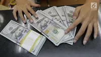 Teller menghitung mata uang dolar di penukaran uang di Jakarta, Jumat (20/4). Nilai tukar rupiah terhadap dolar Amerika Serikat (AS) mengalami pelemahan. (Liputan6.com/Angga Yuniar)