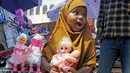 Seorang gadis muda memegang boneka yang dibelikan ibunya untuknya di pasar jalanan ketika keluarga berbelanja untuk hari libur Idul Fitri, yang menandai akhir bulan puasa Ramadhan, di Mogadishu, Somalia, (19/5/2020). (AP Photo/Farah Abdi Warsameh)