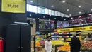 Pelanggan berjalan melewati layar yang menunjukkan kurs dolar AS harian di sebuah supermarket di Beirut, Rabu (1/3/2023). Lebanon mulai memberi harga barang-barang di supermarket dalam dolar AS pada Rabu karena nilai pound Lebanon mencapai posisi terendah baru. (AP Photo/Hussein Malla)