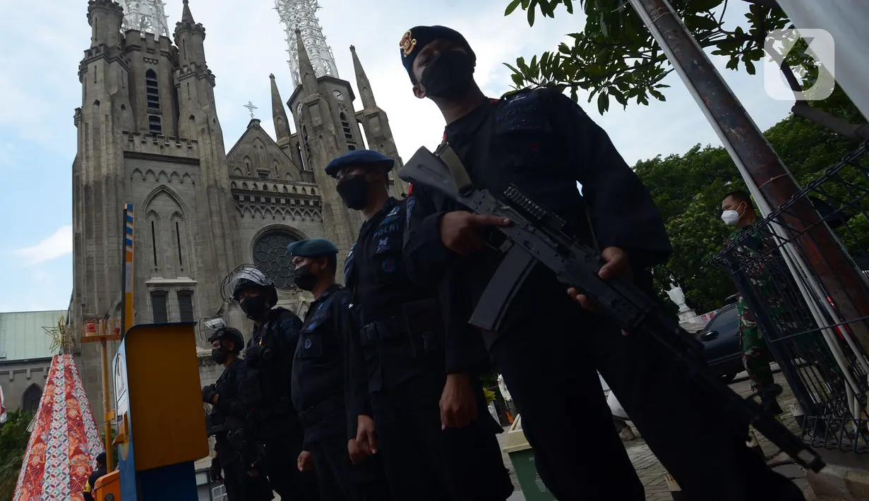 Personel Brimob berjaga di pintu masuk Gereja Katedral, Jakarta, Jumat (24/12/2021). Gereja Katedral menggelar ibadah Natal selama dua hari secara offline dan online. (merdeka.com/Imam Buhori)