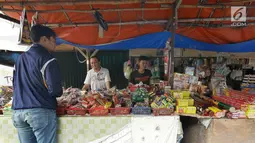 Pedagang melayani pembeli petasan di pasar gembrong, Jakarta, Senin (11/6). Imbas meledakanya pabrik petasan di tanggerang beberapa waktu lalu, harga petasan dan kembang api naik saat menjelang Lebaran 2018. (Liputan6.com/Herman Zakharia)