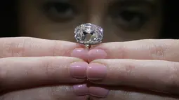Seorang karyawan Balai Lelang Christie berpose dengan berlian merah muda di London, 17 Oktober 2017. Berlian yang akan dilelang tersebut dikenal dengan nama Le Grand Mazarin dan  memiliki berat mencapai 19,07. (AP Photo/Tim Ireland)