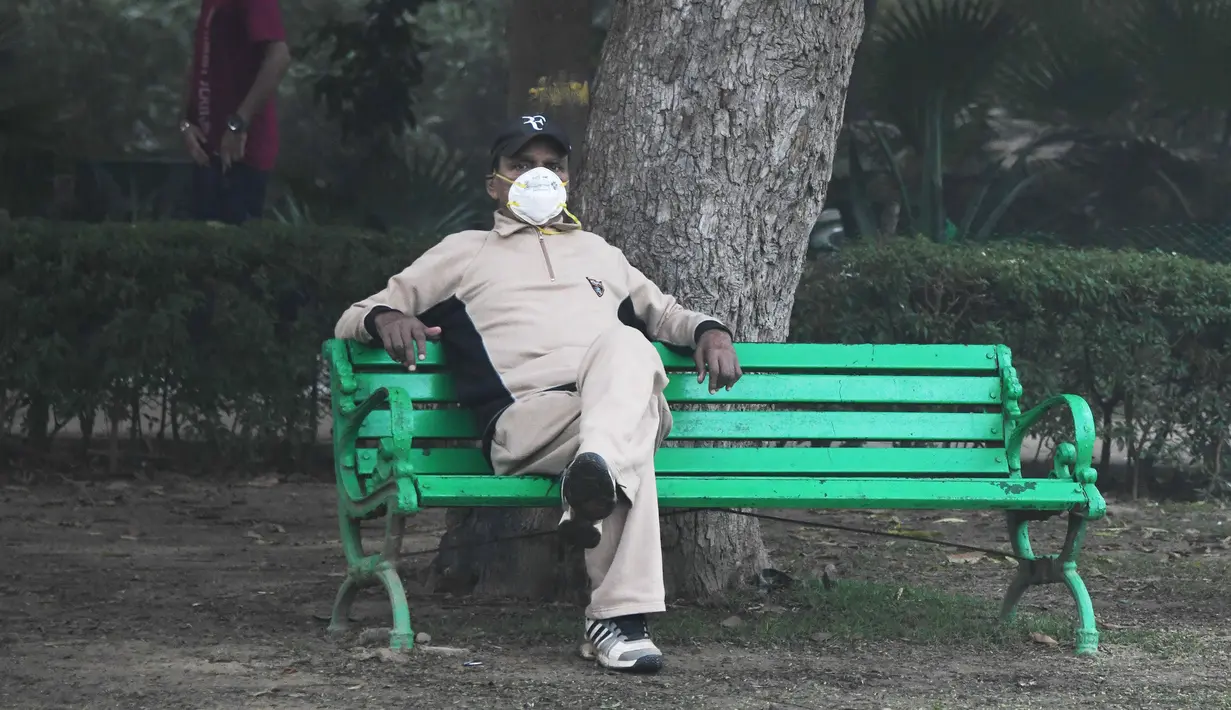 Seorang pria India mengenakan masker untuk melindungi di tengah kondisi kabut asap tebal di Lodhi Gardens di New Delhi (30/10). (AFP Photo/Dominique Faget)
