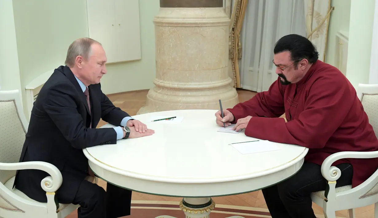 Aktor AS, Steven Seagal menandatangani paspor miliknya yang diberikan Presiden Vladimir Putin di Kremlin di Moskow, Rusia,(25/11). Diketahui Steven mempunyai hubungan dekat dengan Vladimir Putin dan Rusia. (Sputnik/Kremlin/Alexei Druzhinin via REUTERS)
