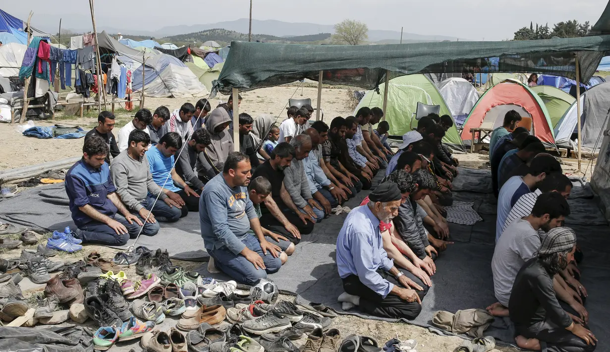Sejumlah imigran saat menggelar salat Jumat di sebuah kamp darurat perbatasan Yunani-Makedonia,desa Idomeni, Yunani (8/4). Meski tengah mencari perlindungan, mereka tak melalaikan kewajibannya sebagai seorang muslim. (REUTERS/Marko Djurica)