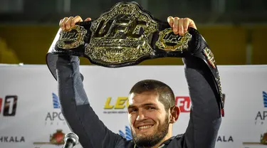 Foto pada 8 Oktober 2018, juara kelas ringan UFC Khabib Nurmagomedov dari Rusia mengangkat sabuk juara setibanya di Makhachkala. Khabib Nurmagomedov mengumumkan pensiun dari dunia seni bela diri campuran (MMA) seusai mengalahkan Justin Gaethje dalam UFC 254, Minggu (25/10/2020). (Vasily MAXIMOV/AFP)