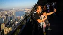 Seorang pria berswafoto dengan bayinya di sepanjang jalur pendakian di Hong Kong pada 22 Februari 2020. Warga Hong Kong memilih pergi ke daerah gunung dan jalur hiking dibandingkan harus tinggal di pusat kota yang sempit dan dibayangi ketakutan akan wabah virus corona (Covid-19). (VIVEK PRAKASH/AFP)