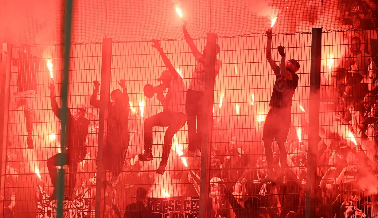 Para suporter PSG menyalakan flare setelah berakhirnya laga pekan ke-37 Liga Prancis 2022/2023 menghadapi Strasbourg di Stade de la Meinau, Strasbourg, Prancis (27/5/2023). Bermain imbang 1-1, PSG memastikan merebut gelar juara Liga Prancis 2022/2023. (AFP/Patrick Hertzog)
