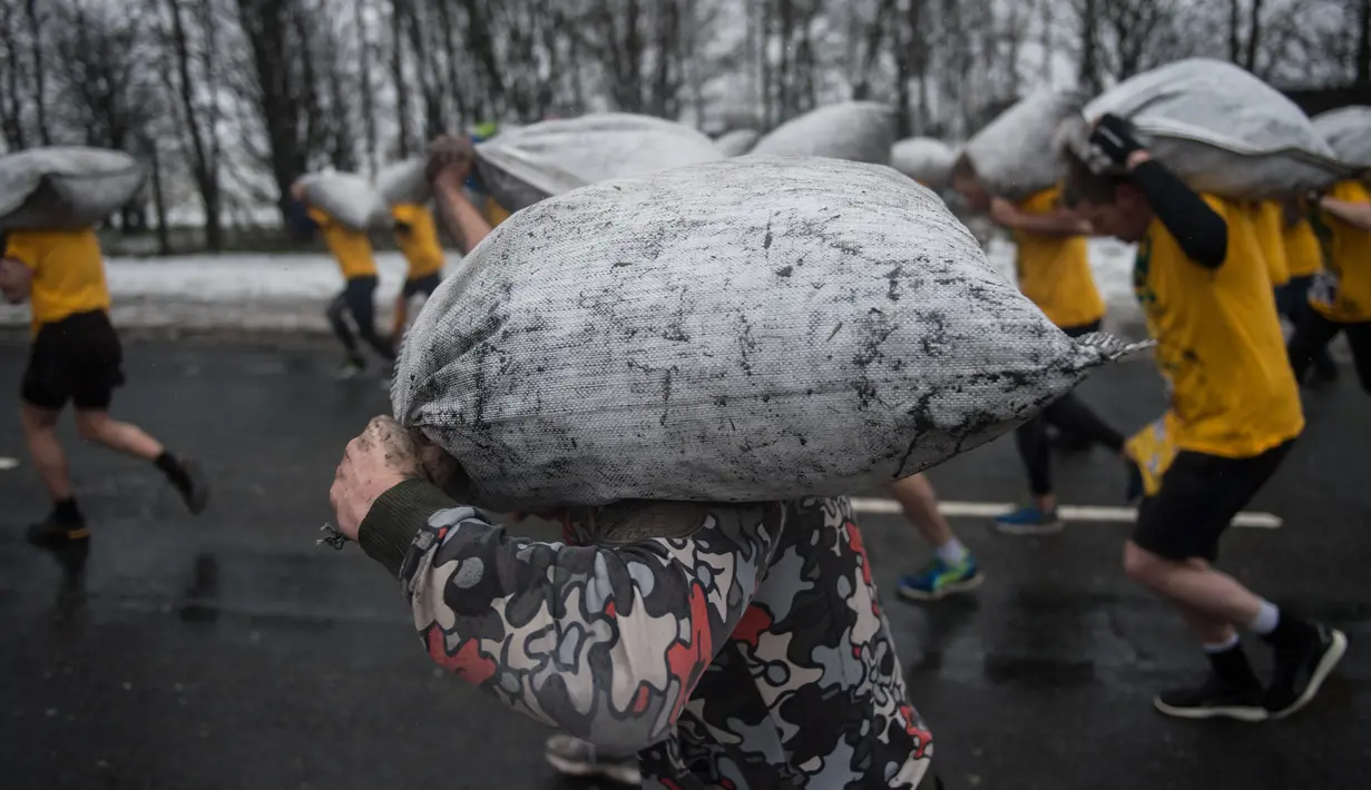 Peserta berlari membawa karung berisi batu bara saat mengikuti World Coal Carrying Championships di Desa Gawthorpe, Wakefield, Inggris Utara, Senin (2/4). Beban yang harus dibawa pria adalah 50 kilogram, sedangkan wanita 20 kilogram. (OLI SCARFF/AFP)