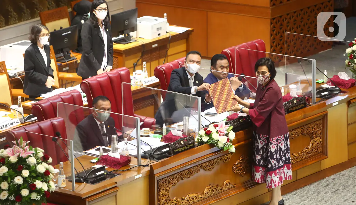 Pimpinan DPR menerima berkas tanggapan pemerintah dari Menteri Keuangan Sri Mulyani (kanan) saat rapat paripurna DPR Ke-10 masa Persidangan II Tahun Sidang 2021-2022 di Kompleks Parlemen, Senayan, Jakarta, Selasa (7/12/2021). (Liputan6.com/Angga Yuniar)