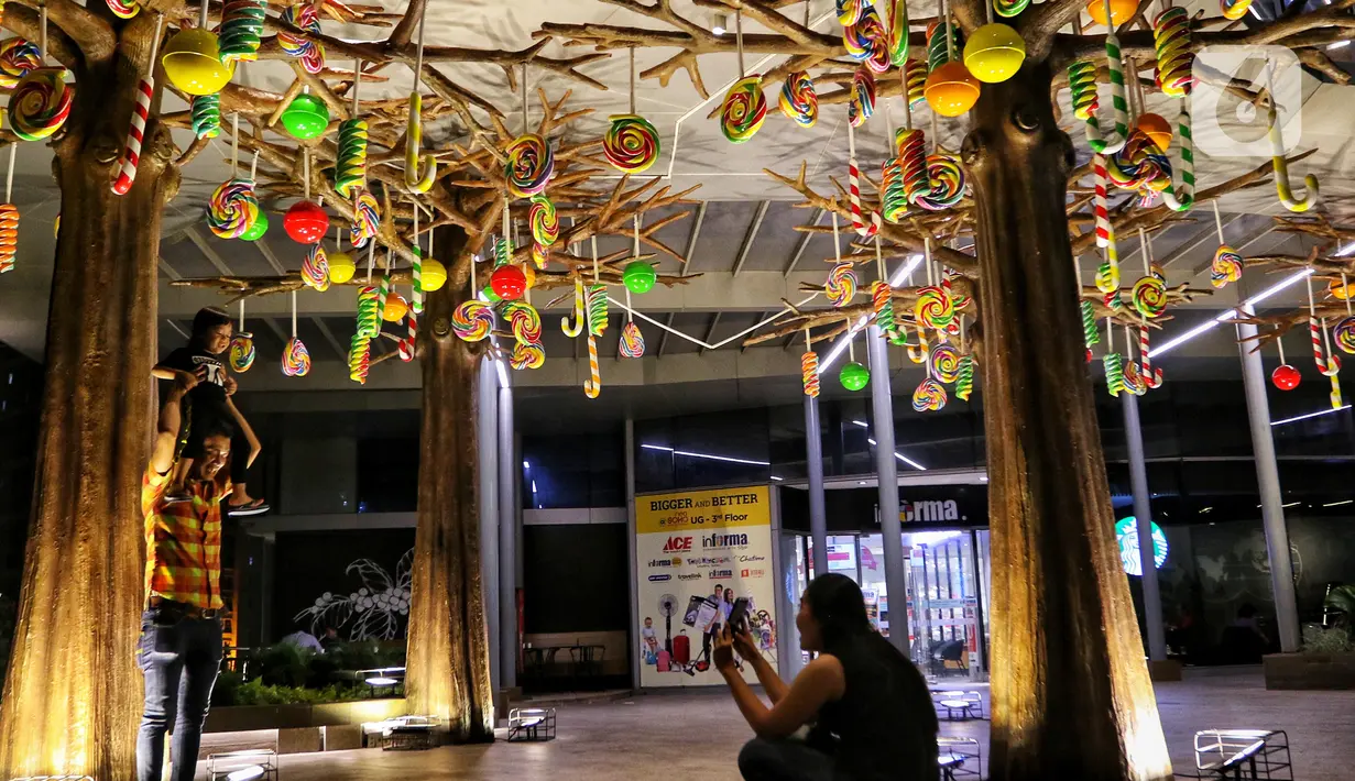 Pengunjung berfoto dengan dekorasi Natal menghiasi mal Central Park, Jakarta, Rabu (11/12/2019). Sejumlah pusat perbelanjaan di Jakarta mulai memasang dekorasi Natal untuk menarik minat pengunjung agar datang dan berbelanja. (Liputan6.com/Johan Tallo)