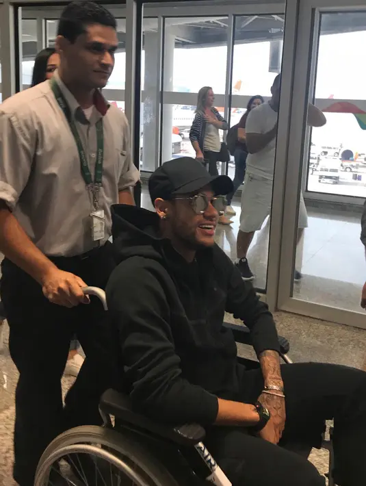 Pemain Paris Saint-Germain (PSG), Neymar menggunakan kursi roda setibanya di bandara Rio de Janeiro, Brasil, Kamis (1/3). Neymar mengalami retak tulang metatarsal saat Olympique Marseille dalam lanjutan Liga Perancis. (Claire Dorland Clauzel via AP)