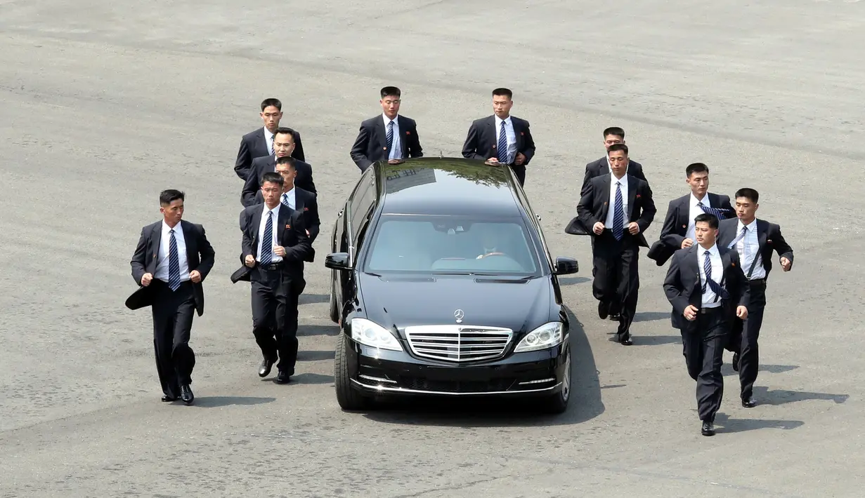 Para pengawal berlari di samping mobil yang membawa Pemimpin Korea Utara Kim Jong-un saat akan makan siang dalam KTT Korea Selatan-Korea Utara di zona demiliterisasi, Panmunjom, Korea Selatan, Jumat (27/4). (Korea Summit Press Pool/AFP)