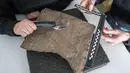 Para peneliti memeriksa runestone yang ditemukan di Tyrifjorden, di Museum Sejarah Budaya di Oslo, pada 12 Januari 2023. Dikatakan, temuan itu "di antara prasasti rahasia tertua yang pernah ditemukan" dan "runestone tertua yang dapat didata di dunia." (Javad Parsa/NTB Scanpix via AP)