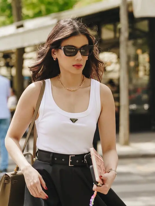 Di sini, Sabrina Chairunnisa terlihat sangat cantik dengan gaya Parisian chic. Ia mengenakan tank top putih, dipadu midi skirt hitam yang mengembang, dan belt hitam. Detail seperti sunglasses dan sling bagnya juga semakin mempermanis keseluruhan penampilannya. Foto: Instagram.