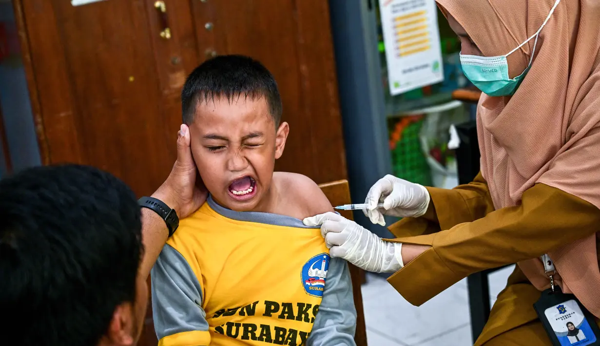 Seorang murid bereaksi saat menerima vaksin difteri di sebuah sekolah dasar di Surabaya pada Selasa 4 November 2025. Melalui kegiatan ini, pemerintah berupaya memastikan anak-anak terlindungi dari penyakit menular yang dapat dicegah melalui imunisasi, sekaligus menjaga kekebalan komunal di lingkungan sekolah. (Juni KRISWANTO/AFP)
