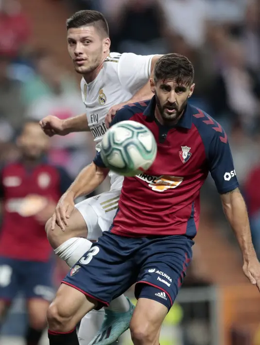 Penyerang Real Madrid, Luka Jovic berebut bola dengan pemain Osasuna, Raul Navas  pada lanjutan pertandingan La Liga di stadion Santiago Bernabeu, Spanyol (25/9/2019). Real Madrid menang 2-0 atas Osasuna. (AP Photo/Bernat Armangue)