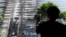 Seorang penghuni apartemen mengambil gambar Gedung Neo Soho pasca kebakaran di Tanjung Duren, Jakarta, Kamis (10/11). Kebakaran Gedung yang masih dalam tahap pembangunan itu terjadi Rabu (9/11) sekitar pukul 20.30. (Liputan6.com/Gempur M. Surya)