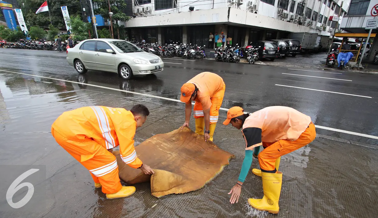 Petugas menggunakan busa untuk membersihkan genangan air di Harmoni, Jakarta, Selasa (9/2). Buruknya sistem drainase membuat petugas terpaksa harus membersihkan genangan setiap kali hujan, meski dengan peralatan seadanya. (Liputan6.com/Immanuel Antonius)