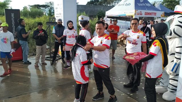 Para PJU Polres Garut menjadi panitia lomba ikut mengalungkan medali fun run kepada peserta yang telah menyentuh garis finis dalam fun run HUT Bhayangkara di jalan Ibrahim Aji, Garut. (Liputan6.com/Jayadi Supriadin)