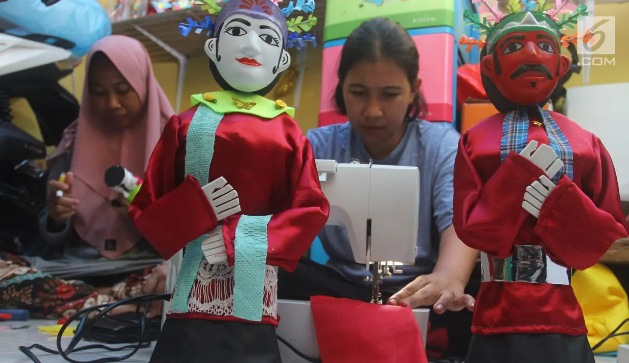Perajin menyelesaikan pembuatan miniatur ondel-ondel di rumah produksi Kramat Jati, Jakarta, Senin (23/6/2019). Perajin bisa mengumpulkan omzet mencapai Rp 5 juta hingga Rp 8 juta per bulan. (merdeka.com/Arie Basuki)