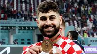 Bek Kroasia, Josko Gvardiol, tersenyum saat menunjukkan medali Piala Dunia 2022 Qatar. (AFP/Jack Guez)