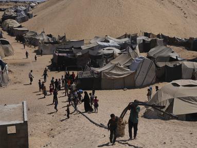Pengungsi Palestina berjalan melalui kamp tenda di Muwasi, kawasan yang telah ditetapkan Israel sebagai zona aman, di Khan Younis, bagian selatan Jalur Gaza, Minggu 21 September 2025. (AP Photo/Jehad Alshrafi)