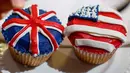 Karyawan memperlihatkan cupcakes edisi khusus untuk menghormati pernikahan Pangeran Harry dan Meghan Markle di Hummingbird Bakery, London, 11 Mei 2018. Pernikahan Harry dan Meghan digelar 19 Mei esok di Kapel St. George, Istana Windsor. (AFP/Tolga AKMEN)