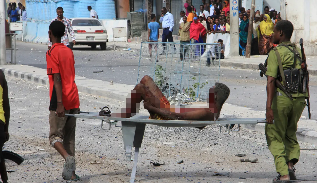 Seorang pria yang terluka dalam serangan bom mobil bunuh diri ditandu oleh petugas Palang Merah Somalia di Mogadishu, Somalia, Rabu (25/1).  Setidaknya 13 orang dilaporkan tewas dan puluhan lainnya terluka dalam kejadian ini. (AP Photo)
