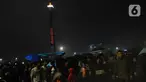 Pengunjung memadati kawasan Monumen Nasional saat malam pergantian tahun, Jakarta, Rabu (1/1/2020). Penampilan video mapping mewarnai kemeriahan malam pergantian tahun baru di kawasan Monumen Nasional, Jakarta. (Liputan6.com/Helmi Fithriansyah)