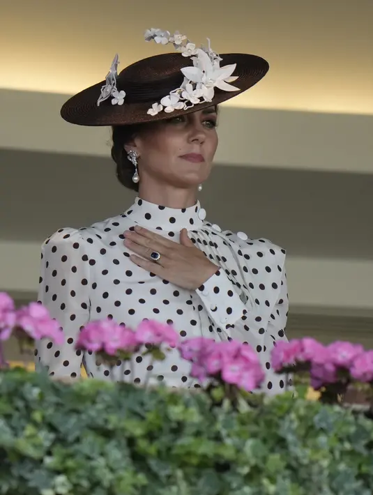 Kate Middleton melihat keluar dari Royal Box pada hari keempat pertemuan pacuan kuda Royal Ascot di Ascot Racecourse, Ascot, Inggris, 17 Juni 2022. Kate Middleton melengkapi penampilannya dengan topi anyaman kecil yang dihiasi bunga-bunga putih. (AP Photo/Alastair Grant)