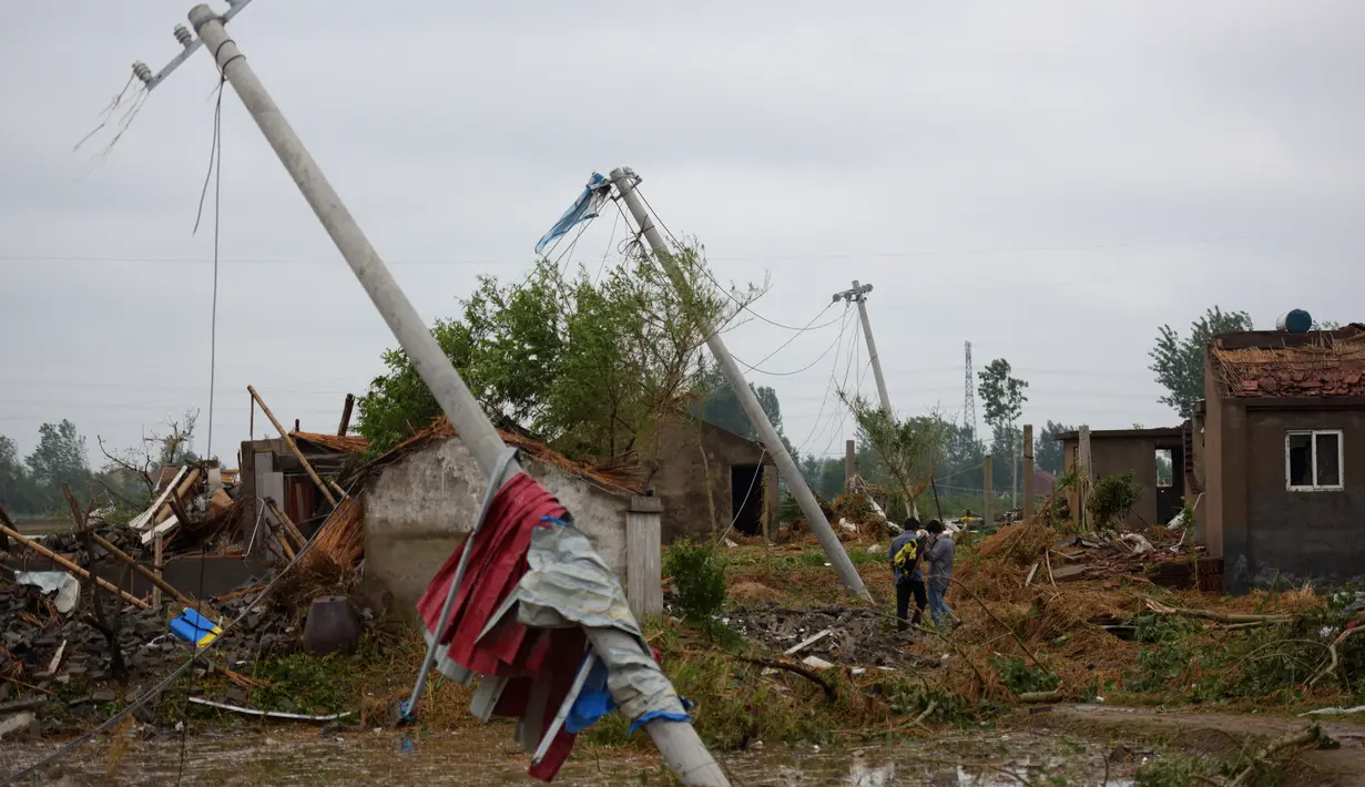 Tiang lampu listrik berserakan di jalan akibat tornado yang menyapu wilayah Yancheng, Provinsi Jiangsu, Tiongkok, Kamis (23/6). Badai disertai hujan es telah menyebabkan kekacauan di Jiangsu. (JOHANNES EISELE/AFP)