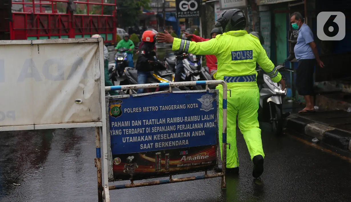Petugas kepolisian mengatur lalu lintas saat melakukan penutupan jalan KH Hasyim Ashari, Kota Tangerang, Banten, Sabtu (16/7/2022). Akibat banjir yang merendam kawasan tersebut membuat petugas harus menutup jalur dan memutarbalikan para pengendara yang melintas. (Liputan6.com/Angga Yuniar)