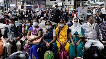 Orang India yang menunggu di stasiun kereta api memakai masker pelindung sebagai tindakan pencegahan terhadap pandemi Virus Corona.
