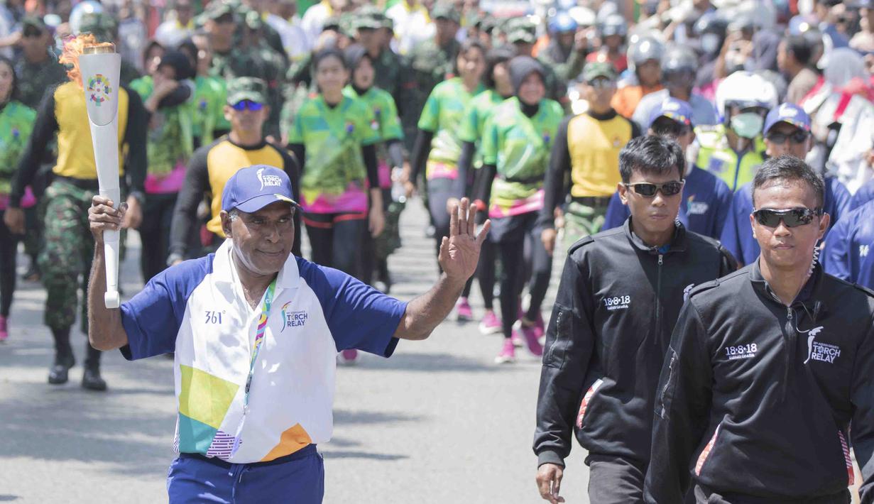 Legenda taekwondo Indonesia, Abdul Rojak, membawa obor Asian Games saat melintasi di Banjarmasin, Kalimantan Selatan, Senin (30/7/2018). Sebanyak 53 kota di Indonesia akan dilalui oleh obor Asian Games. (Bola.com/Reza Bachtiar)