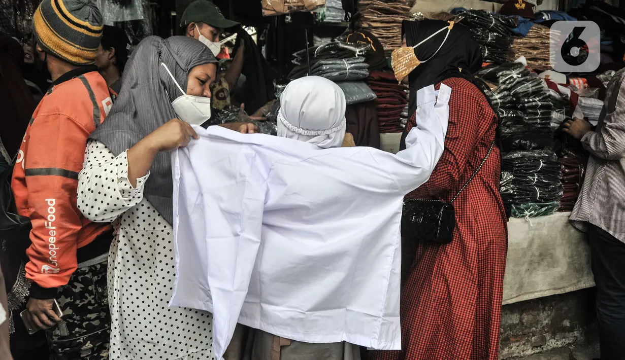 Seorang anak saat mencoba seragam sekolah di Pasar Mester Jatinegara, Jakarta Timur, Senin (3/1/2022). Salah satu pedagang mengungkapkan penjualan seragam sekolah mengalami peningkatan 50 persen seiring pemberlakuan PTM di Jakarta yang kembali digelar 100 persen. (merdeka.com/Iqbal S. Nugroho)
