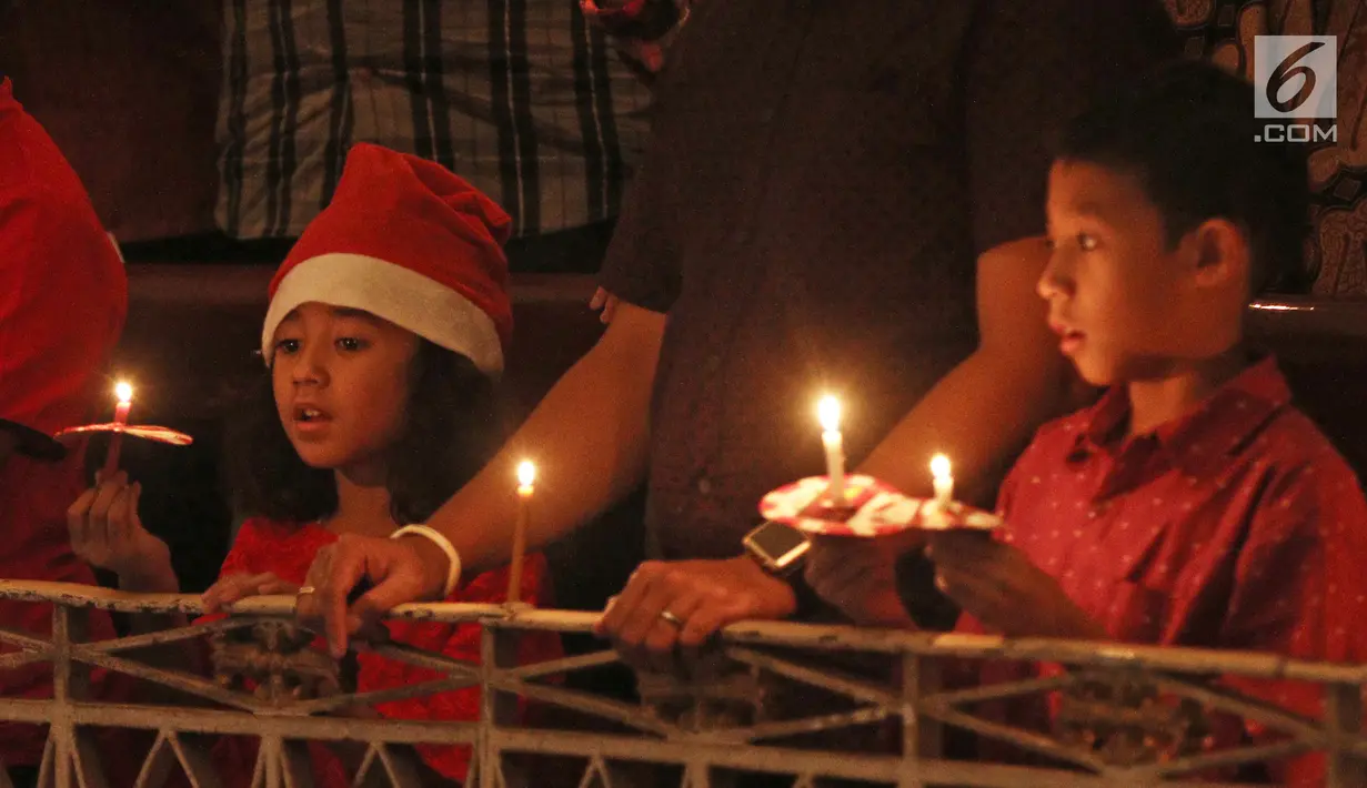 Dua anak memegang lilin pada Misa Natal di Gereja Protestan Indonesia Barat (GPIB) Immanuel, Gambir, Jakarta, Minggu (24/12). Misa Natal 2017 mengusung tema Damai Sejahtera. (Liputan6.com/Herman Zakharia)