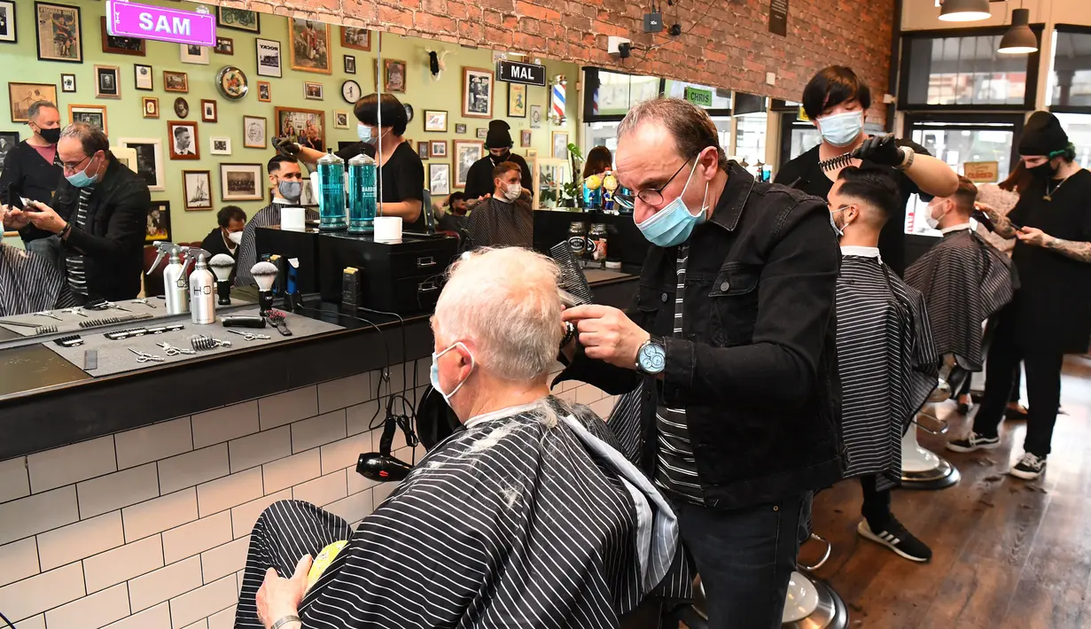 Para pria memotong rambut di barber shop di Melbourne, Australia, Senin (19/10/2020). Warga Kota Melbourne, pada Senin (19/10), akhirnya bisa bernafas lega saat sejumlah pembatasan dilonggarkan setelah menjalani lockdown tahap keempat yang ketat selama sekitar 100 hari. (William WEST/AFP)