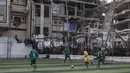 Setiap teriakan dari pinggir lapangan menjadi pengingat, di balik getirnya kehidupan di Gaza, ada jiwa-jiwa yang menolak menyerah. Tampak dalam foto, warga Palestina menyaksikan pertandingan sepak bola lima lawan lima di tengah reruntuhan bangunan yang hancur di Kota Gaza pada Senin 9 Februari 2026. (Omar AL-QATTAA/AFP)