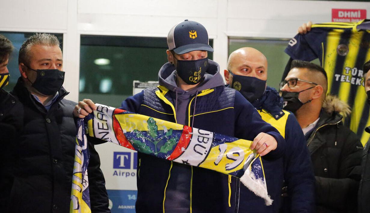 Pesepak bola asal Jerman, Mesut Ozil, menunjukan syal Fenerbahce saat tiba di Bandara Ataturk, Turki, Senin (18/1/2021). Setelah memutuskan hengkang dari Arsenal, Ozil akan memperkuat klub asal Turki, Fenerbahce. (AP Photo)
