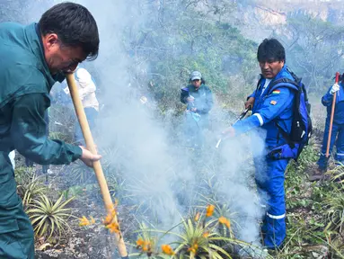 Presiden Bolivia Evo Morales (kanan) menyemprotkan air saat berusaha memadamkan api dalam kebakaran hutan di pinggiran Robore, Bolivia, Selasa (27/8/2019). Morales menunda kampanye pilpres untuk terjun langsung memadamkan api. (Raul Martinez/Bolivia's Communication Ministry press office via AP)