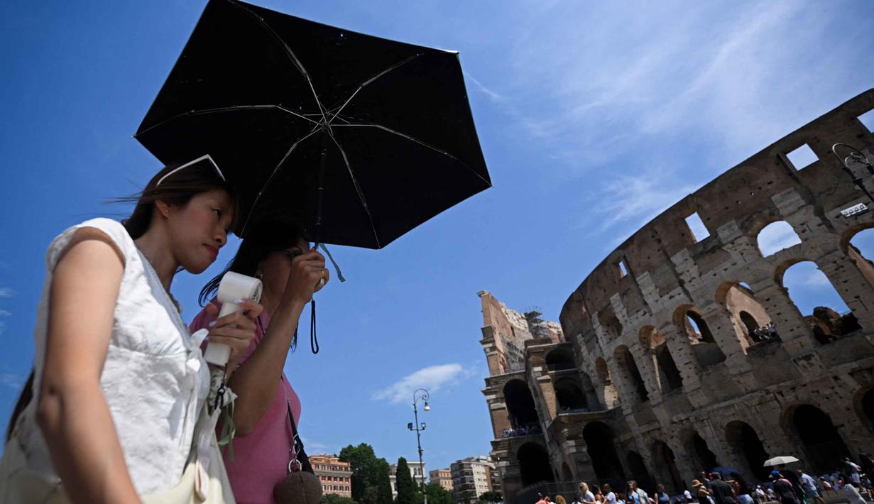 Orang-orang melindungi diri dari terik matahari dengan payung di dekat Koloseum selama gelombang panas awal musim di Roma pada Kamis 28 Mei 2026. (Tiziana FABI/AFP)