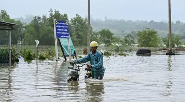 Seorang pria mendorong sepedanya melewati jalanan yang tergenang air di kota Hpa Yar Gyi di wilayah Bago, Myanmar, pada tanggal 9 Oktober 2023. (SAI AUNG MAIN/AFP)