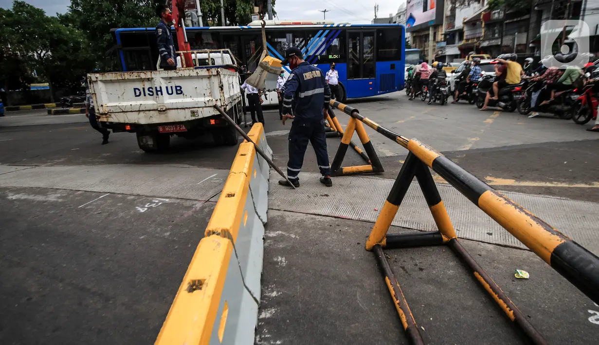 Petugas Dinas Perhubungan DKI Jakarta menurunkan beton barrier saat penutupan akses jalan menuju kawasan Kota Tua, Jumat (18/12/2020). Pemprov DKI membatasi moda transportasi melintasi kawasan wisata Kota Tua seiring penerapan kawasan rendah emisi atau Low Emission Zone. (Liputan6.com/Johan Tallo)