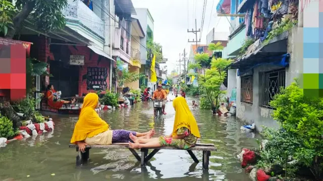 Warga Sidoarjo bersantai di sela banjir yang merendam rumahnya. (Istimewa)