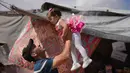 Abdullah Al-Hurkali bermain dengan putrinya, Tasneem, selama Hari Raya Idul Adha di sebuah kamp tenda untuk pengungsi Palestina di Khan Younis, Jalur Gaza, Rabu 27 Mei 2026. (AP Photo/Abdel Kareem Hana)