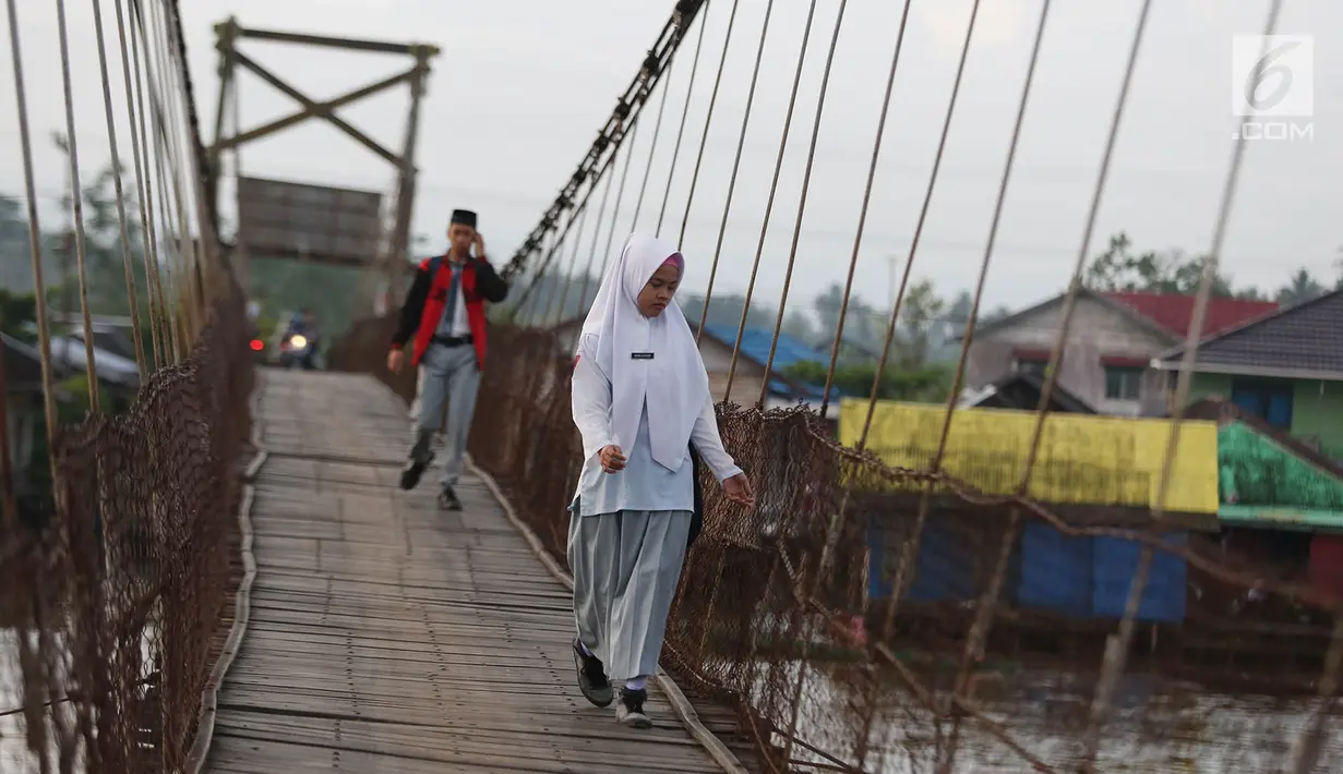 Dua orang pelajar melintasi jembatan penyeberangan di Sungai Martapura, Banjarmasin, Kalimantan Selatan, Selasa (27/3). (Liputan6.com/Immanuel Antonius)