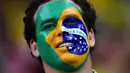 Supporter Brasil mewarnai wajahnya saat menonton laga kualifikasi Piala Dunia 2018 melawan Uruguay di Recife, Brasil, Sabtu (26/3/2016) pagi WIB. Kedua tim bermain imbang 2-2. (AFP/Christophe Simon)