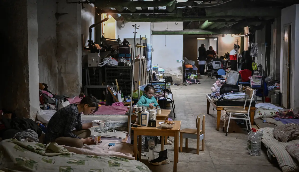 Anak-anak yang dirawat di rumah sakit pediatri ditempatkan tempat tidur mereka di ruang bawah tanah rumah sakit yang digunakan sebagai tempat perlindungan bom di Kiev, Senin (28/2/2022). Tentara Rusia mengatakan, warga sipil Ukraina dapat meninggalkan ibu kota Kiev dengan bebas. (Aris Messinis / AFP