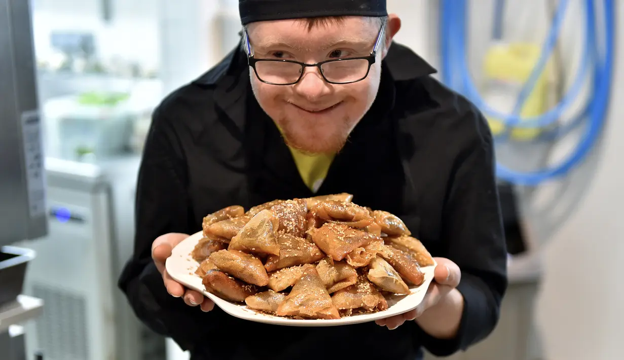 Asisten memasak down sindrom memegang sepiring kue Maroko pesanan pengunjung restoran "Le Reflet" di Nantes, Prancis Barat, 9 Februari 2017. Lelievre (26), mempekerjakan sejumlah karyawan yang memiliki down syndrome di restorannya. (LOIC VENANCE/AFP)